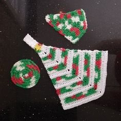 a crocheted christmas tree ornament and bauble on a black surface