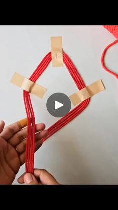 someone is making an origami house out of red string