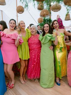 a group of women standing next to each other on a wooden floor in front of a white tent