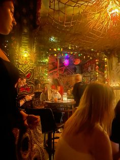 a group of people sitting at tables in a room with many lights on the ceiling