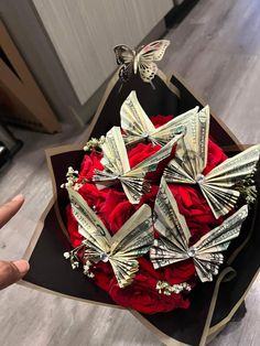 a bouquet of red roses and dollar bills in the shape of butterflies