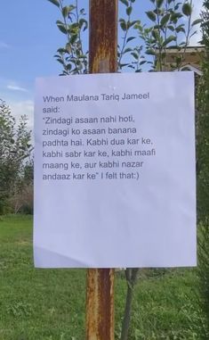 a sign posted on a pole in the grass