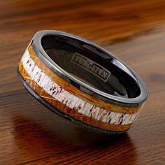 a wedding band with wood and silver inlays on a wooden table, made to look like an antelope ring