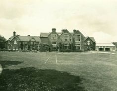 an old black and white photo of a tennis court in front of a large house