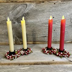 three candles are sitting next to each other on a wooden table with candy canes