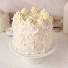 a white frosted cake sitting on top of a table next to a bottle of milk