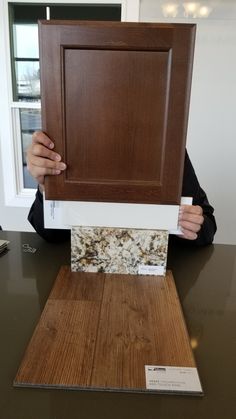 a person holding up a piece of wood that is on top of a countertop