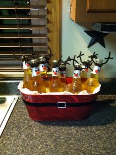 six bottles of beer sitting in a red cooler with reindeer antlers on the top