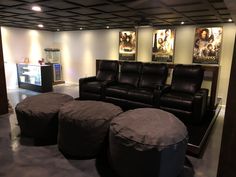 a living room filled with black leather furniture and pictures on the wall above it's two recliners