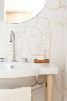 a white sink sitting under a bathroom mirror next to a wooden shelf with a towel on it