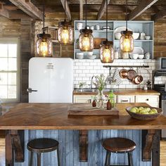 a kitchen island with stools in front of it and lights hanging from the ceiling