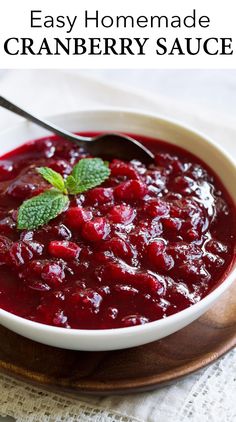 cranberry sauce in a white bowl on a wooden plate with a spoon next to it