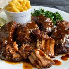 a white plate topped with meat covered in gravy next to chips and greens