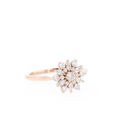 an 18k rose gold ring set with round brilliant cut diamonds in the center, on a white background