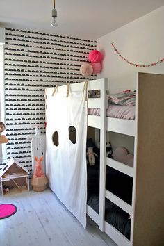 a child's bedroom with black and white wallpaper, bunk beds and pink rugs