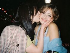 two young women are kissing each other in front of a cityscape at night