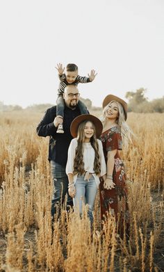 a man, woman and child are standing in the middle of a field with tall grass