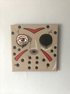 a painting of a mask with eyes and nose holes on the side of a wall