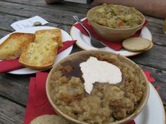 a table topped with plates of food and bowls filled with stew next to slices of bread