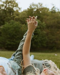 a woman laying in the grass with her hands up