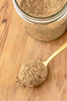 a wooden spoon with some brown stuff in it next to a jar on a table