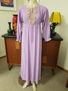 Romantic style long length night gown in a soft wash n wear ankle length. The night gown is in a nylon muted mauve with long sleeves and ruffle cuff, round neck with a lace ruffle in beige and bronze, three button closure,  empire line , and ankle length. The label is Diamond Cut and made in Australia. The size is 14au. The condition is very good with no faults found  Measurements are Shoulder to shoulder 43cm Bust approx 91cm Length shoulder to hem 144cm  Sleeves shoulder to cuff 56cm Full Length Gown With Lace Trim, Elegant Long Sleeve Lace Sleepwear, Lace Long Sleeve Sleepwear For Wedding Night, Fitted Lace Robe For Loungewear, Feminine Fitted Robe With Lace Trim, Fitted Feminine Robe With Lace Trim, Purple Long Sleeve Gown For Spring, Elegant Fitted Long Sleeve Sleepwear, Long Sleeve Purple Gown For Spring