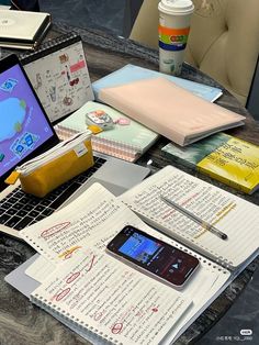 an open laptop computer sitting on top of a table next to notebooks and papers