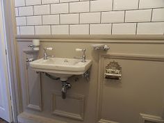 a white sink sitting under a bathroom mirror next to a doorway with a light on it