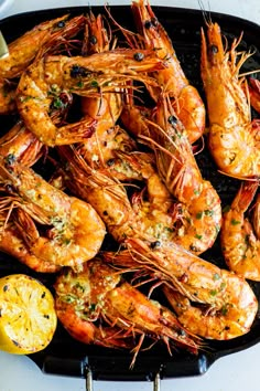 grilled shrimp with lemon wedges and parsley on a black grilling pan