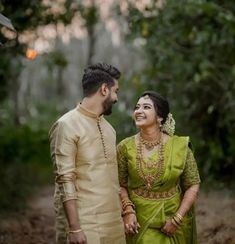 a man and woman standing next to each other in the woods