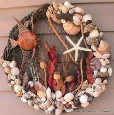 a wreath made out of seashells and other sea life is hanging on the side of a house