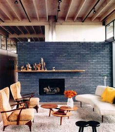 a living room filled with furniture and a fire place next to a brick wall covered in windows