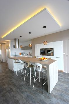 a modern kitchen with an island and bar stools next to the counter top that has fruit on it