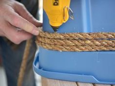 a person using a drill to attach rope on a blue container with a yellow screwdriver