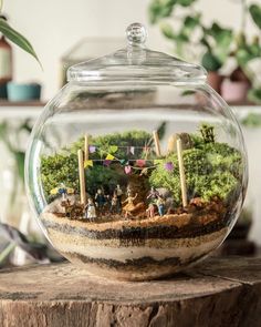 a glass bowl filled with miniature people and trees