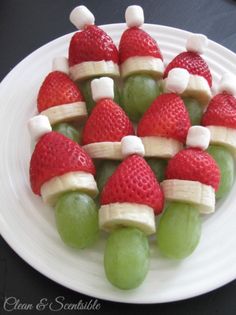 some fruit is arranged in the shape of santa's hats on a white plate