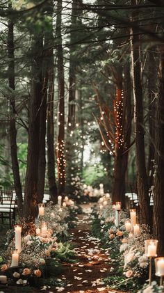 an outdoor ceremony with candles and flowers on the ground, surrounded by tall pine trees