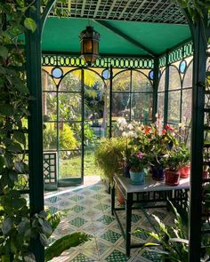 the inside of a green house with potted plants and flowers on the table in front of it