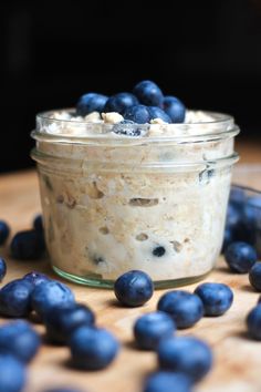 a bowl of oatmeal with blueberries scattered around it on a wooden table