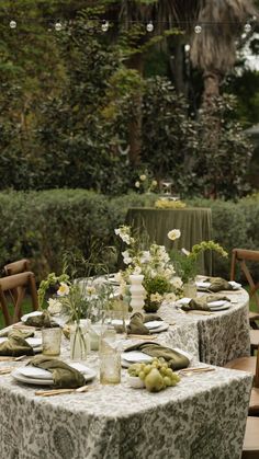 the table is set with plates and vases on it, along with other place settings