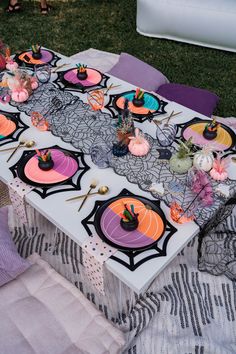 a table with halloween decorations on it in the middle of some grass and purple blankets