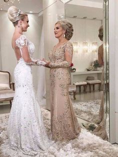 two women standing in front of a mirror and one is wearing a dress with flowers on it