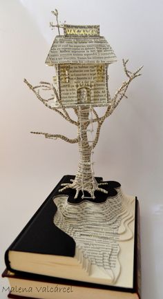 a book with a tree on top of it and a house made out of books