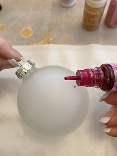 someone is painting an ornament with pink and white acrylic on it