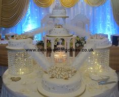 a large white cake on top of a table with lights in front of the cake