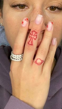 a woman is holding her hand up to her face with tattoos on the fingers and hands