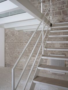 an empty room with white stairs and brick walls