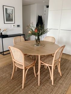 a dining room table with chairs and a vase filled with flowers on top of it