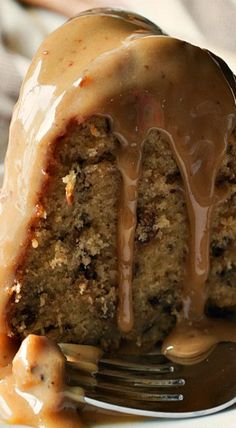 a close up of a piece of cake on a plate with a fork and caramel drizzle