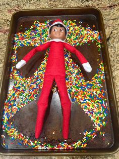 an elf laying on top of a tray filled with sprinkles